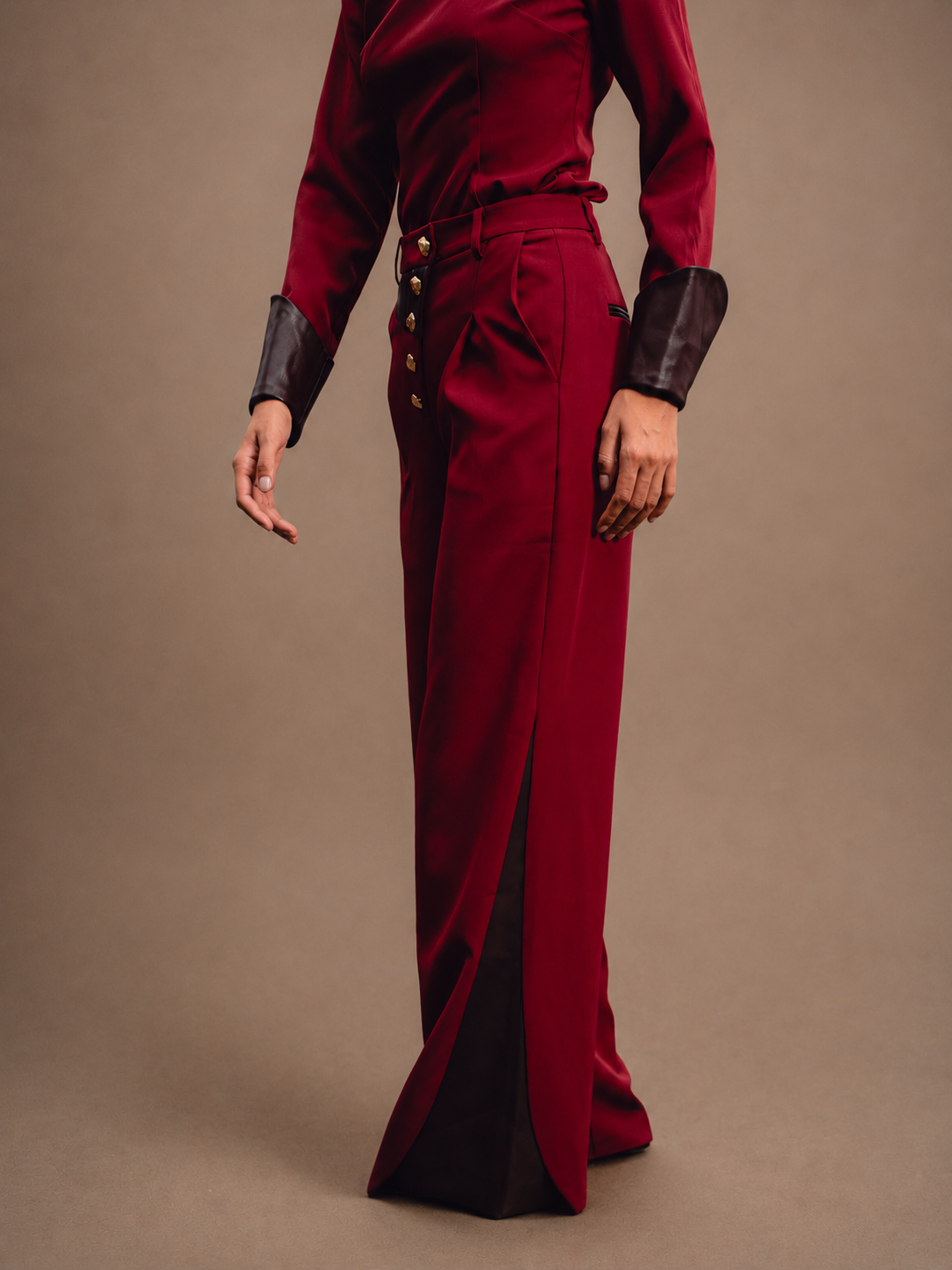 RŪH 04 Leather Trousers with signature gold-tone buttons at the layered waistband